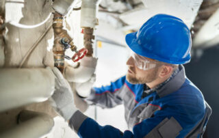 Male Worker Inspecting Water Valve For Leaks In Basement